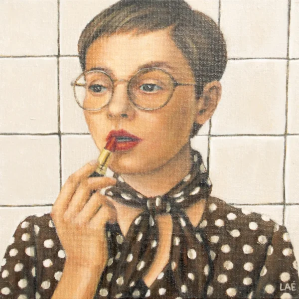 Femme aux cheveux courts et lunettes fines appliquant un rouge à lèvres, chemisier à pois et foulard noué, devant un carrelage blanc.