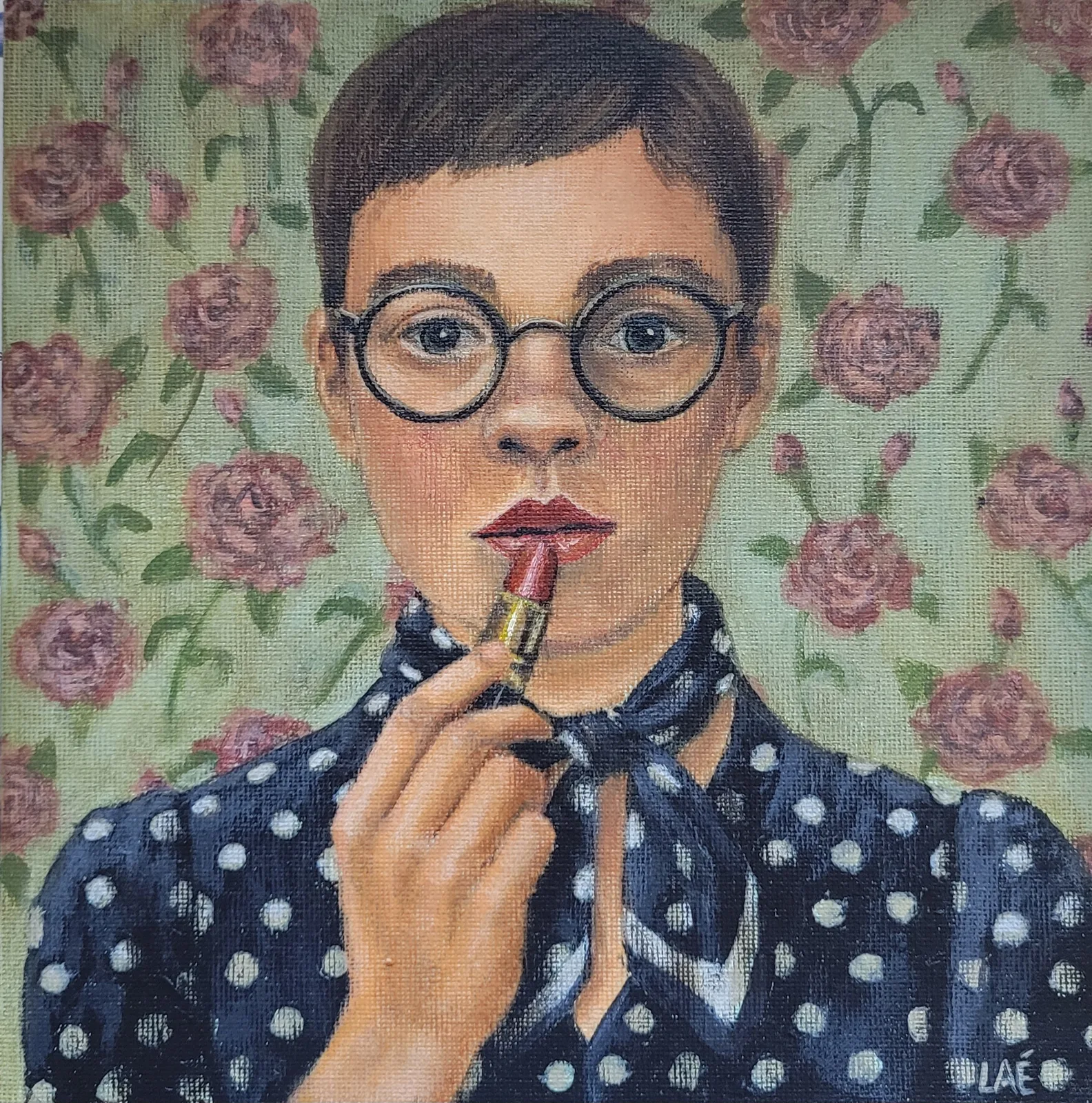 Jeune femme à lunettes rondes appliquant un rouge à lèvres, chemisier à pois marine, devant une tapisserie de roses fanées.