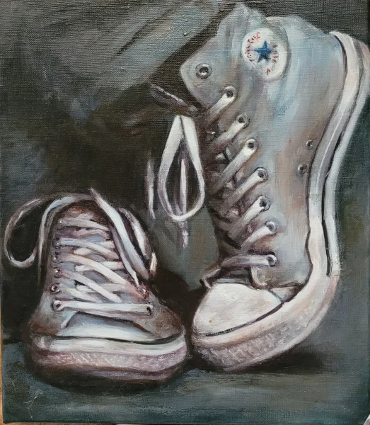 Deux paires de Converse montantes usées, lacets défaits, posées côte à côte sur un fond sombre.