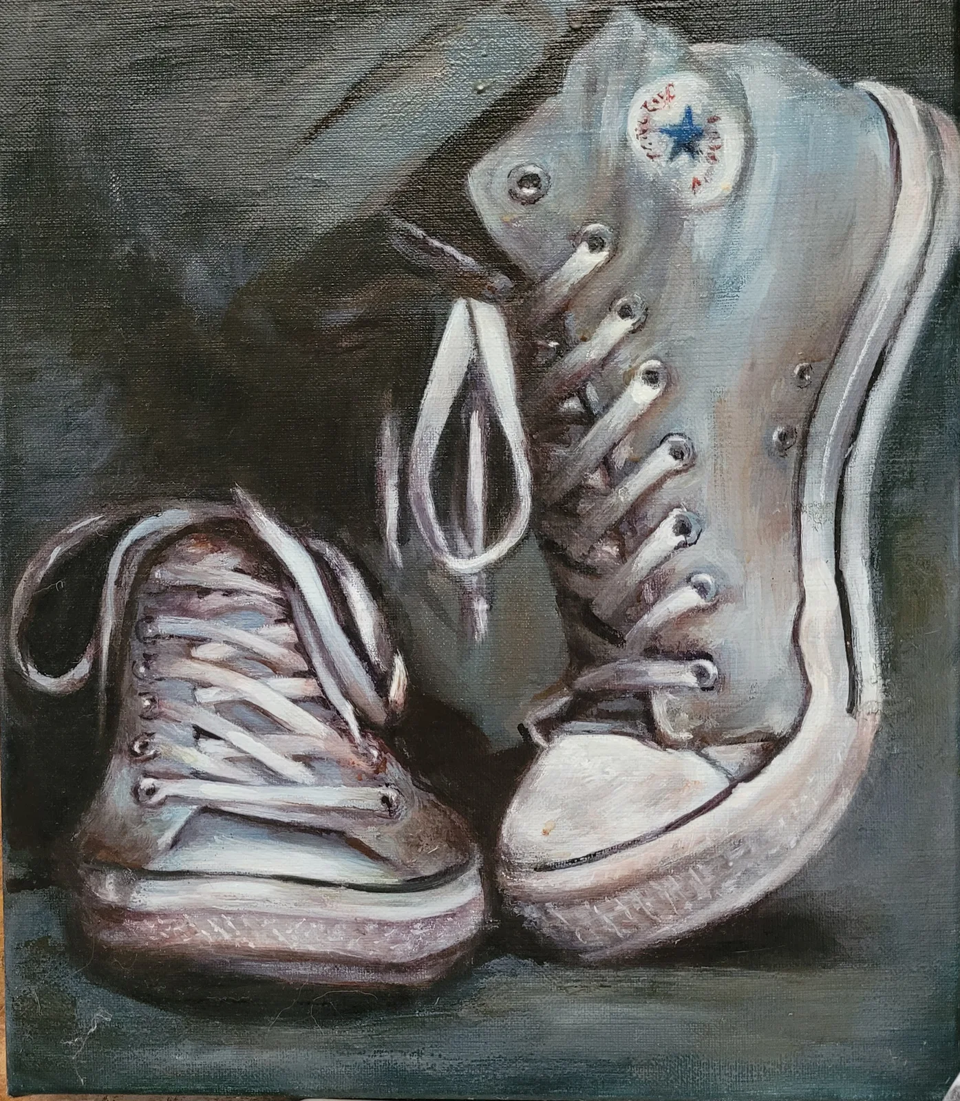 Deux paires de Converse montantes usées, lacets défaits, posées côte à côte sur un fond sombre.