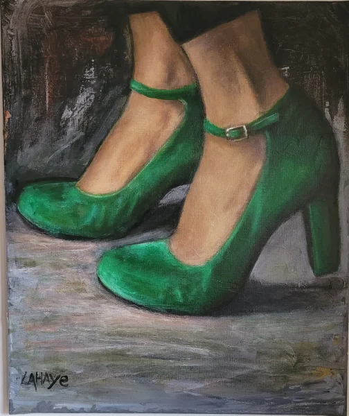 Escarpins vert émeraude à brides et talons carrés, jambes croisées sur un sol gris.